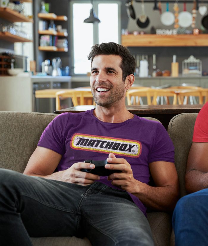 Man wearing purple Matchbox t-shirt playing computer game